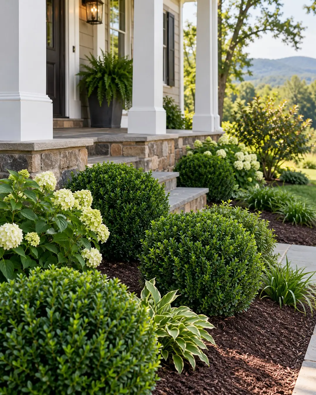 Pruned shrubs and mulched beds beside a porch